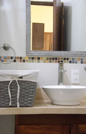 A bathroom with a white sink, a mirror, and a wicker basket on the countertop. - Verde Luna (San Francisco)