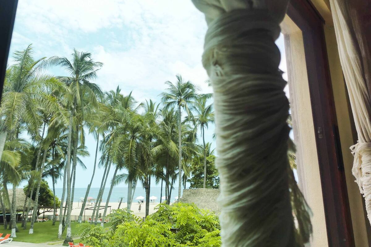 A view of a beach with palm trees and a clear sky.