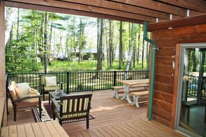 A wooden deck with outdoor furniture, including a sofa, chairs, and a table. - Northwoods Get Away!  Enjoy the privacy of this property & large game room! (Birchwood)