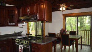 Una cocina con armarios de madera oscura, una estufa de acero inoxidable y un comedor con mesa y sillas.