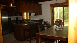 Una cocina con armarios de madera, un refrigerador de acero inoxidable y una zona de comedor con una mesa y sillas.