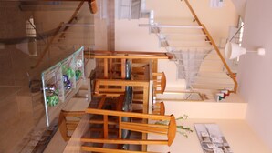 Un interno su più livelli con una scala, ringhiere in legno e una vetrina a sospensione.