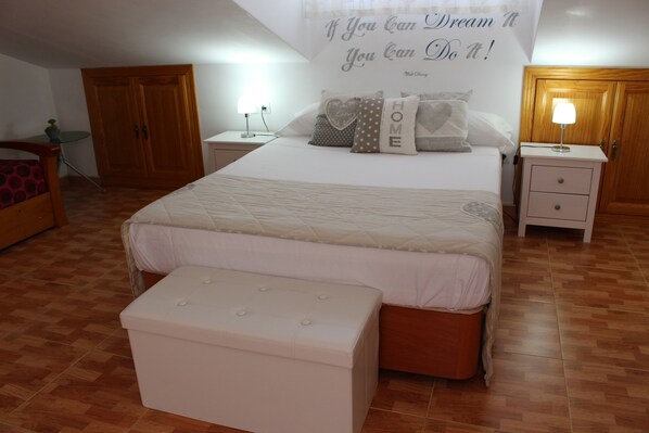 A bedroom with a bed, bedside tables, a nightstand, a bench, and a motivational poster on the wall. - Cozy duplex with sunny terrace (Málaga)