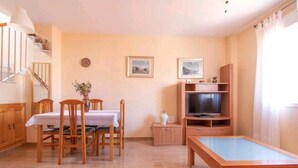 Un soggiorno con tavolo da pranzo, sedie, televisore e tavolo da biliardo.