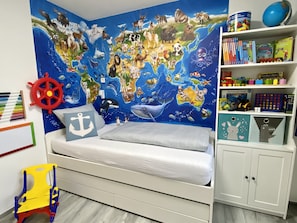 A child's bedroom with a world map mural, a bookshelf with educational toys, and a small desk with a globe.