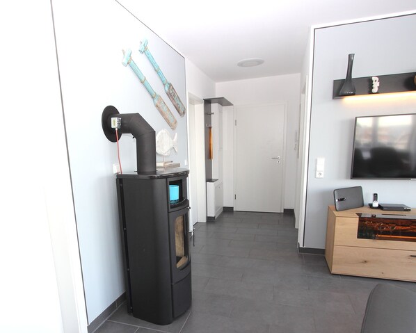 A modern kitchen with a built-in stove, a wooden cabinet, and a flat-screen TV. - For children | Baltic Sea view | playroom | sauna scents | firewood | beach chair (Großenbrode)