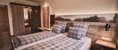 A bedroom with a wooden headboard, a bed with plaid bedding, a nightstand, and a wall-mounted TV.