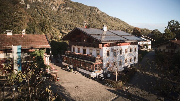 A traditional chalet-style building with a sloped roof, a balcony, and a view of a mountainous landscape.