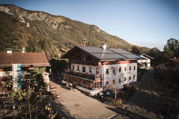 A traditional chalet-style building with a sloped roof, a balcony, and a view of a mountainous landscape.