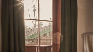 A room with a window, curtains, a radiator, and a sofa. - Raitner Wirt (Schleching)