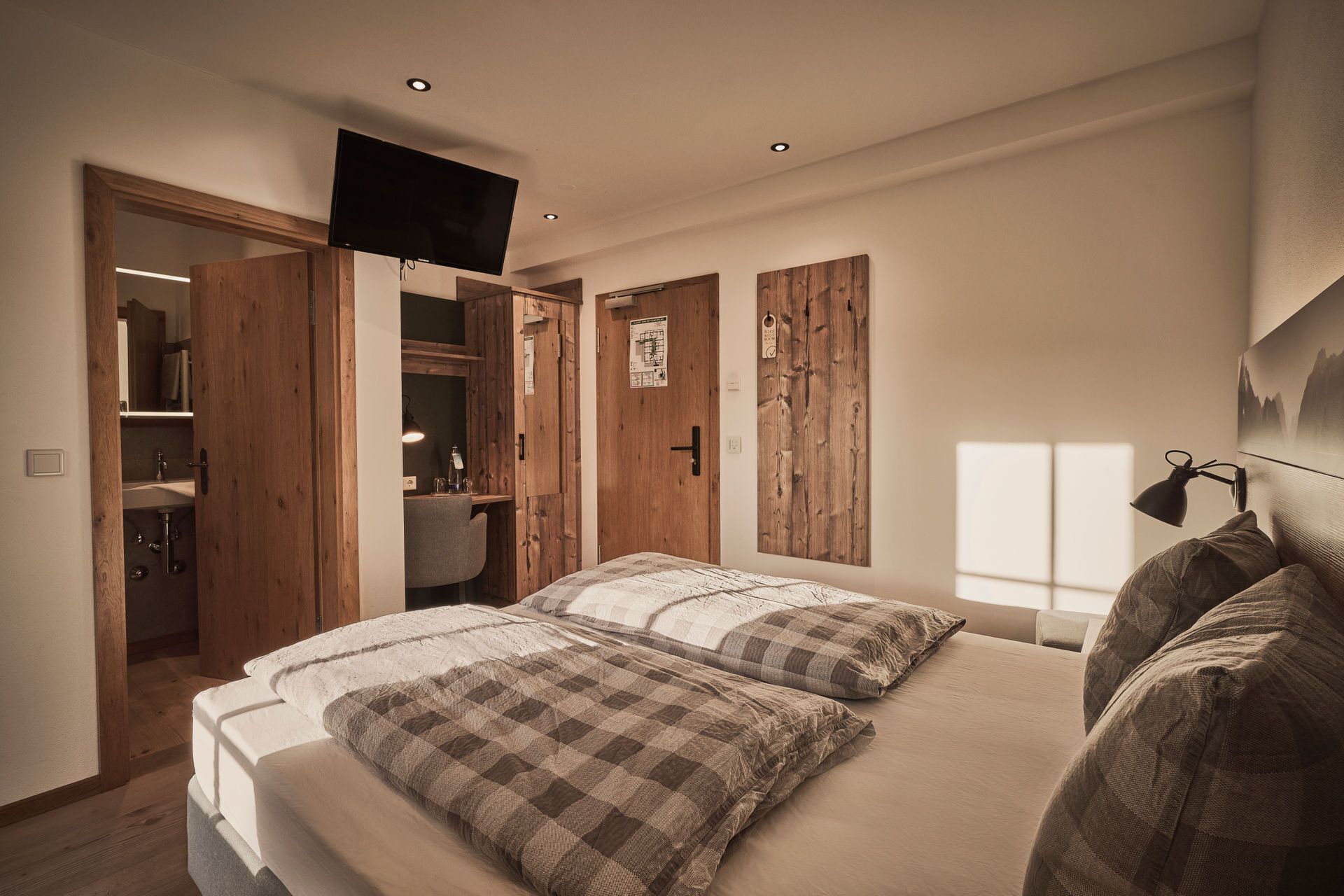 A bedroom with a bed, a desk, and a wardrobe.