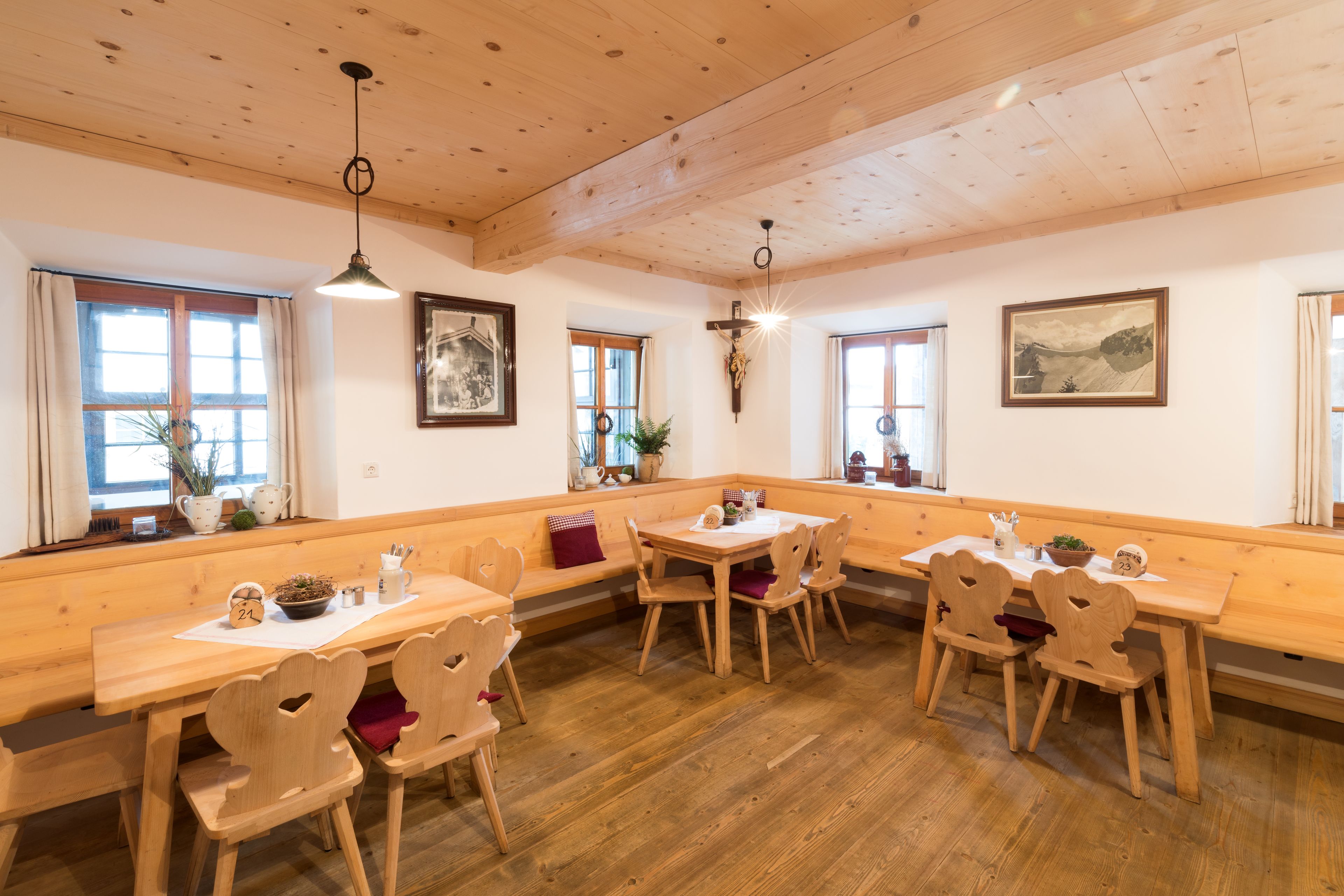 L’intérieur est en bois, avec un plafond haut, des bancs et des tables en bois. On y trouve des fenêtres avec des rideaux, un crucifix au mur et des tableaux encadrés.