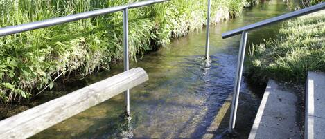 Un sendero de concreto con barandillas metálicas a lo largo de un estrecho canal de agua.