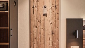 A room with a wooden bench, a wall-mounted coat rack, a small table, and a trash can. - Raitner Wirt (Schleching)