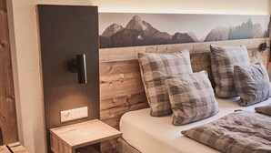 A bedroom with a wooden headboard, a bedside table, and a bed with plaid bedding.