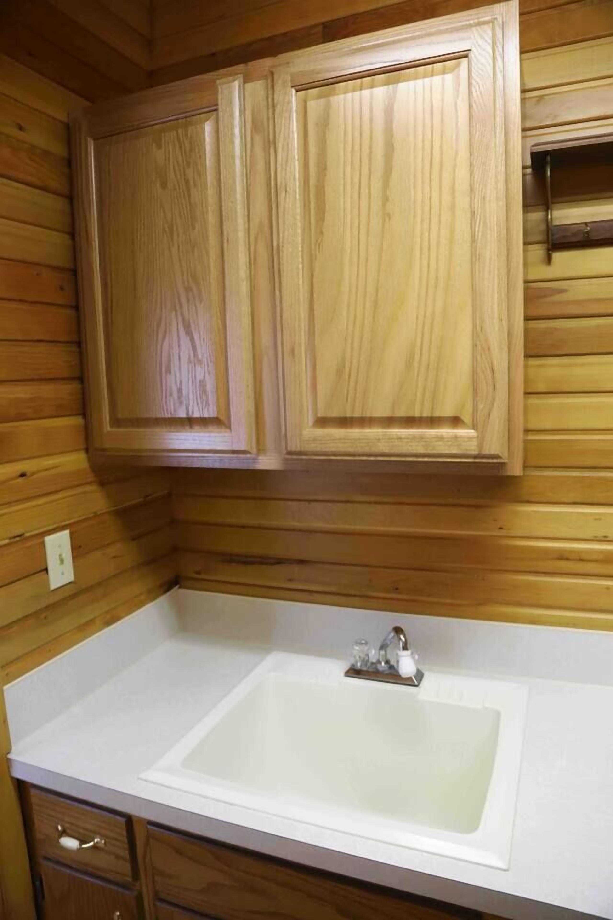 A bathroom with wooden paneling, a white sink, and a cabinet above it.