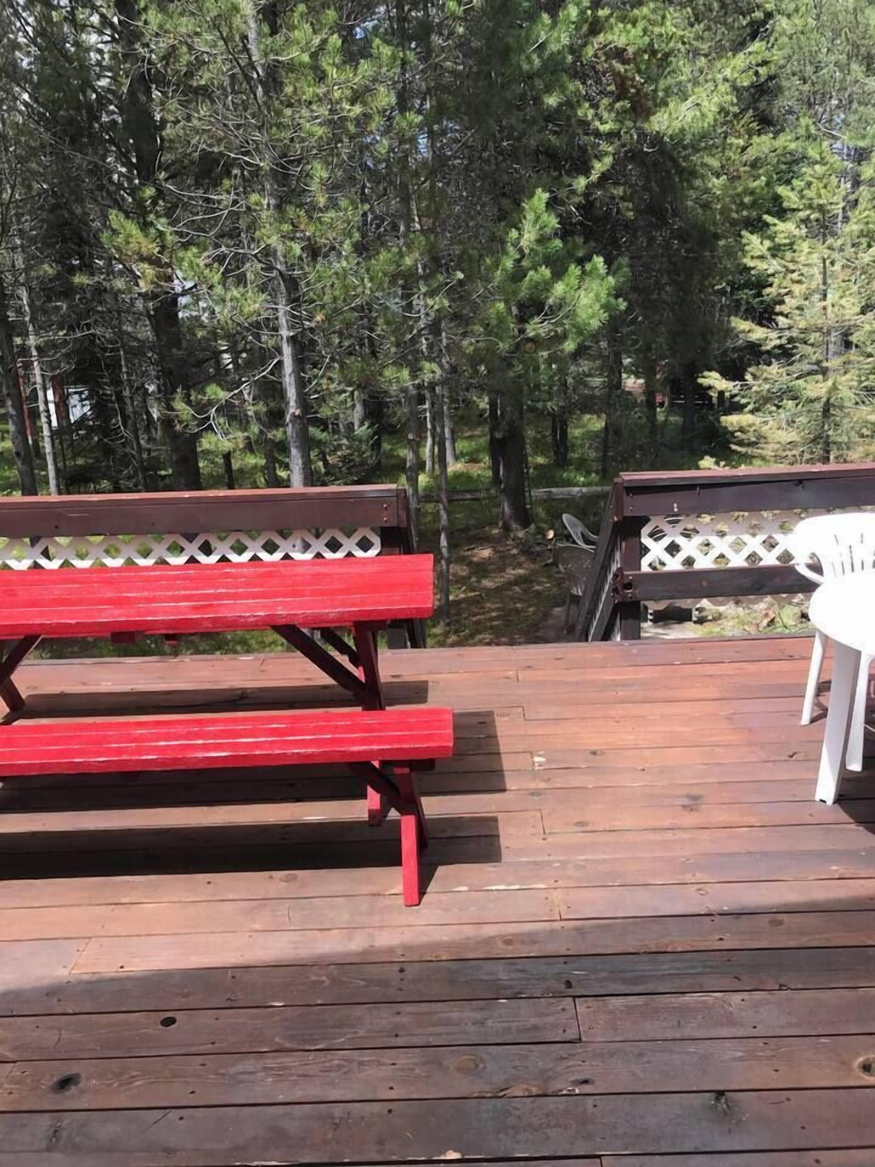 Eine Holzterrasse mit einer roten Bank und einem weißen Stuhl.