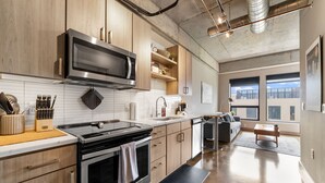A modern kitchen with wooden cabinets, a stainless steel microwave, and a built-in oven. - MINNeSTAY* Sable 603 | North Loop | Target Center (Minneapolis)