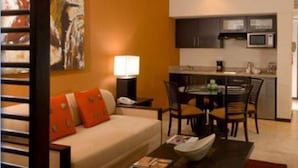 Un espacio habitable compacto con sofá, mesa de comedor, sillas, microondas y pequeña cocina.