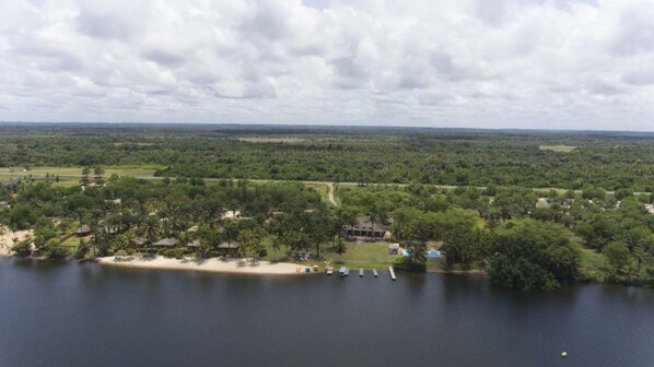 A lakeside property with a swimming area, a path, and a building surrounded by trees.