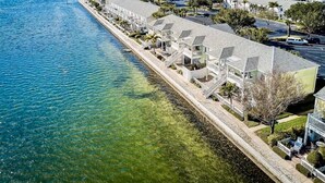 Un hotel frente al mar con una hilera de habitaciones con vista a la playa, una vista despejada del agua y un estacionamiento.