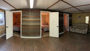 Una habitación con pisos de madera, una escalera central y dos camas con ropa de cama estampada.