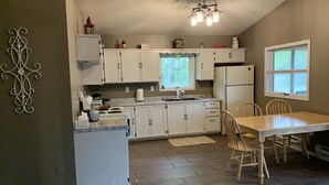 Una cocina con armarios blancos, una mesa de comedor de madera y una araña.