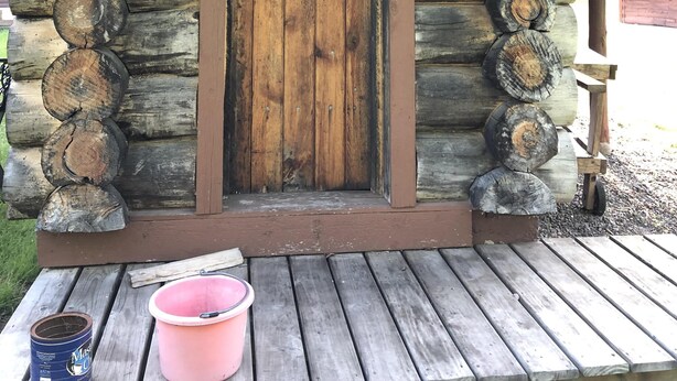Una cabaña rústica de troncos con puerta de madera y un porche.