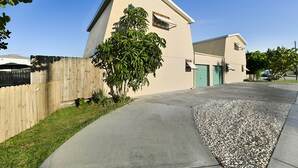 A two-story building with a beige exterior, a wooden fence, and a tree in front.