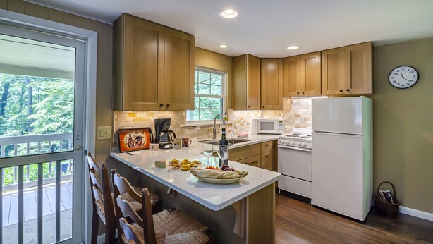 A modern kitchen with wooden cabinets, a central island, a refrigerator, a microwave, and a stove.