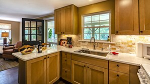A kitchen with wooden cabinets, a large window, and a countertop with various items.