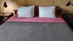 A hotel room with a large bed, two bedside tables, a wall clock, and a painting. - King Bed - MCM Style- Backyard View (Spring Green)