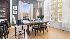 A dining area with a wooden table, black chairs, and a chandelier. - Embrace Comfort and Convenience | Hibiscus House (Charleston)