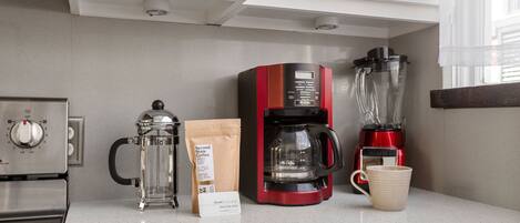 Una cocina con cafetera, licuadora, molinillo de café y una bolsa de café.