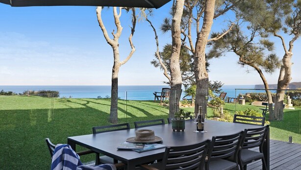 An outdoor dining area with a view of the sea, surrounded by trees and a grassy lawn. - Amazing views and short walk to beach (Copacabana)