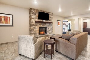 A living room with a stone fireplace, a flat-screen TV, and a comfortable seating area.
