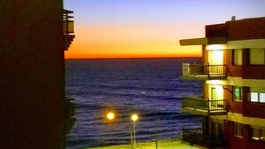 A view of the ocean at sunset with a building on the right. - Edificio Único (Mar del Plata)