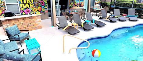 An outdoor pool area with lounge chairs, a tiki bar, and a poolside bar.
