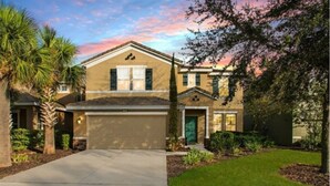 A two-story house with a beige facade, a front garage, and a well-maintained lawn. - Your Disney Family Vacation Resort Home With Private Pool/TikiBar (Davenport)