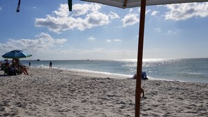 Una playa con sombrillas y gente.