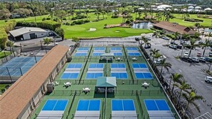Complejo de canchas de tenis en la azotea, con múltiples canchas, zona de estar cubierta y un campo de golf al fondo.