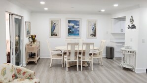Un comedor moderno y bien iluminado con una mesa redonda y sillas, rodeado de paredes blancas y suelo de madera.