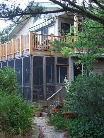 Upper deck faces ocean while lower screened-in porch is nestled in dunes.