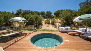 Une terrasse en bois avec une piscine circulaire, des meubles d’extérieur et des parasols.