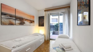 Une chambre avec deux lits, une vue sur l’extérieur et des œuvres d’art accrochées aux murs.