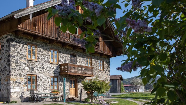 A stone building with wooden balconies and a small garden area.