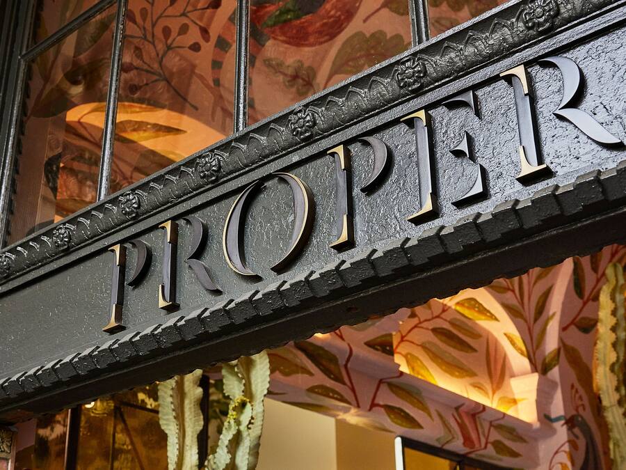 Uma placa com a palavra 'PROPER' em letras grandes e elaboradas.