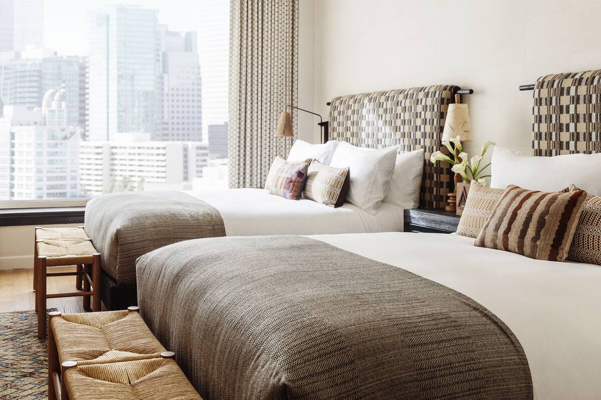 A hotel room with two beds, a view of the city, and a cityscape visible through the window.