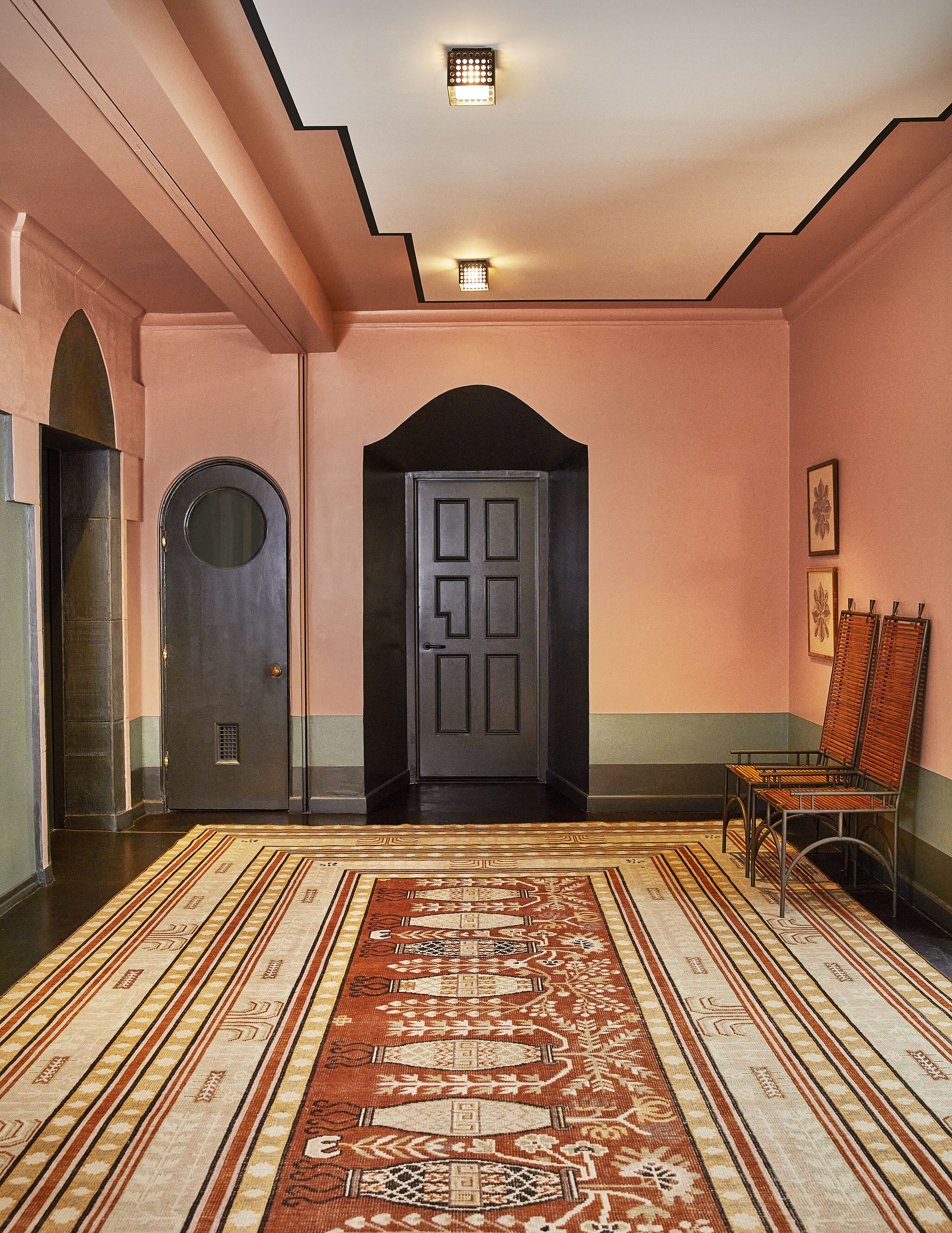 A hallway with a patterned carpet, a dark door, and a bench.