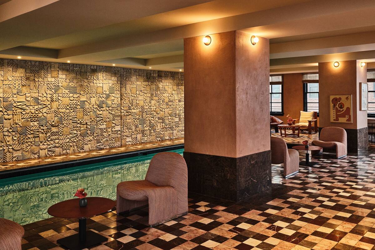 A lobby with a checkered floor, a pool, and a decorative wall.